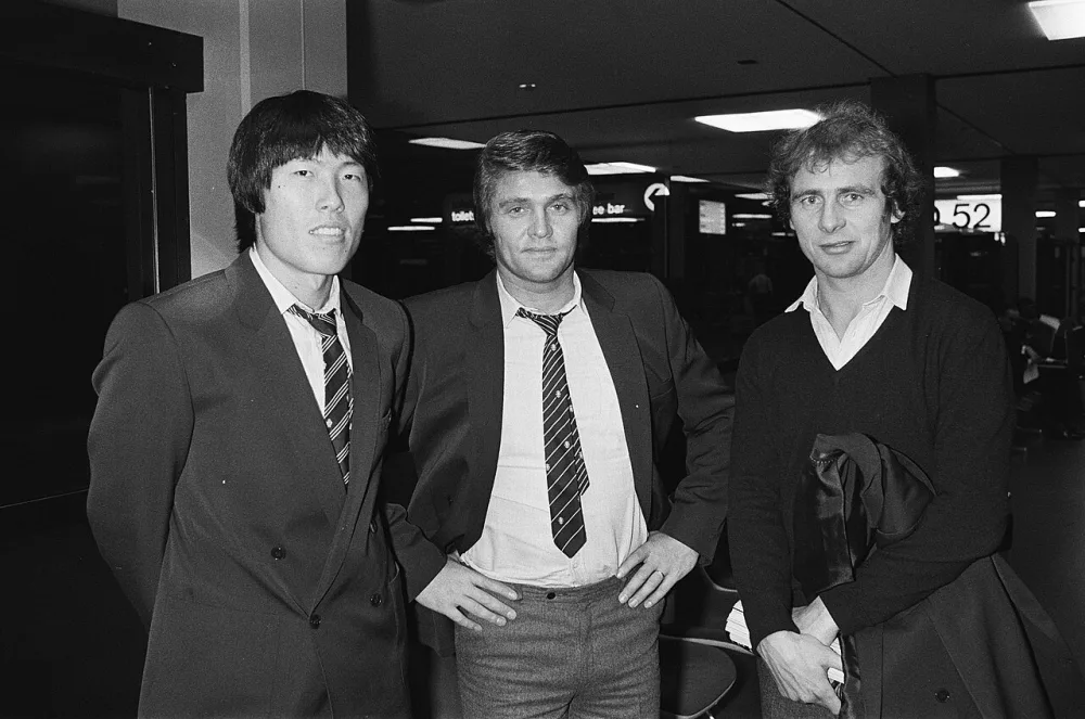 Aankomst van het voetbalelftal van Eintracht Frankfurt op Schiphol i.v.m. de UEFA Cup wedstrijd tegen Feyenoord; v.l.n.r. Cha, trainer Rausch en Hölzenbein. Foto: fotograaf onbekend / Anefo, Nationaal Archief (CC0).