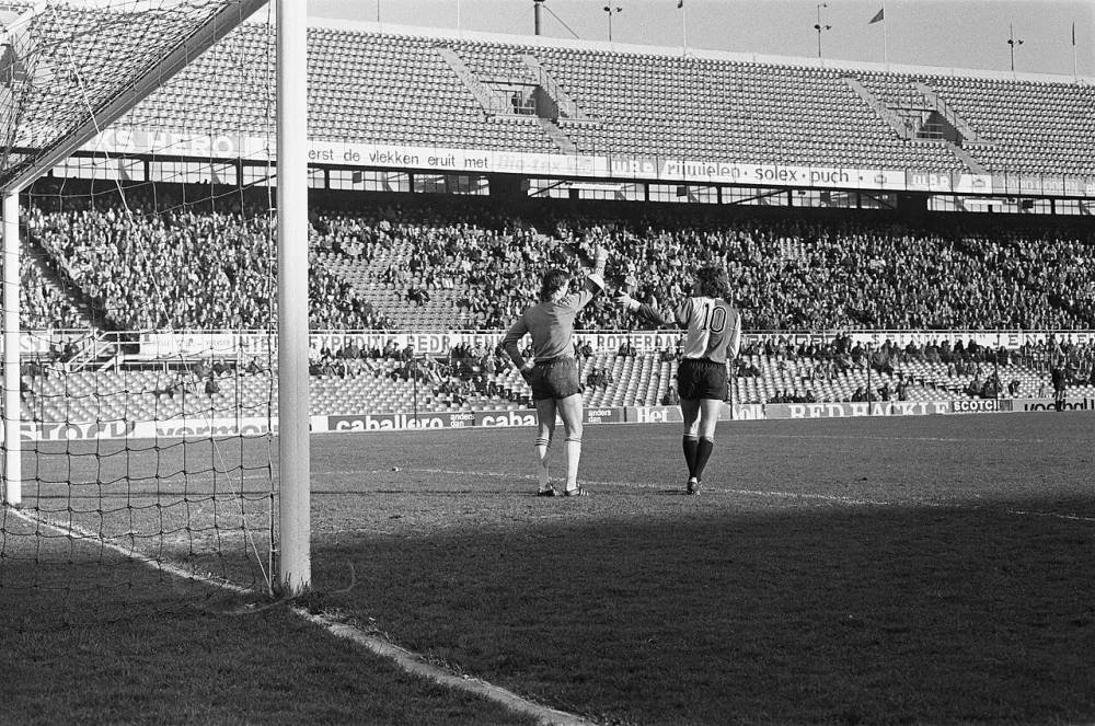 Feyenoord tegen Go Ahead Eagles 3-1, Van Hanegem (r) werpt zonneklep om arm van keeper Rijkens. Foto: Hans Peters / Anefo, Nationaal Archief (CC0).