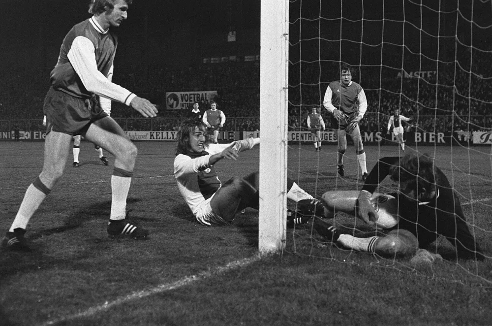 Voetbal. Ajax tegen Feyenoord 2-1. Spelmoment, het eerste doelpunt van Ajax in de 1e minuut. Ger Reitsma is al in de eerste minuut onder toezichtvan Johan Neeskens, na een schot van Johnny Rep…. Foto: Rob Mieremet / Anefo, Nationaal Archief (CC0).