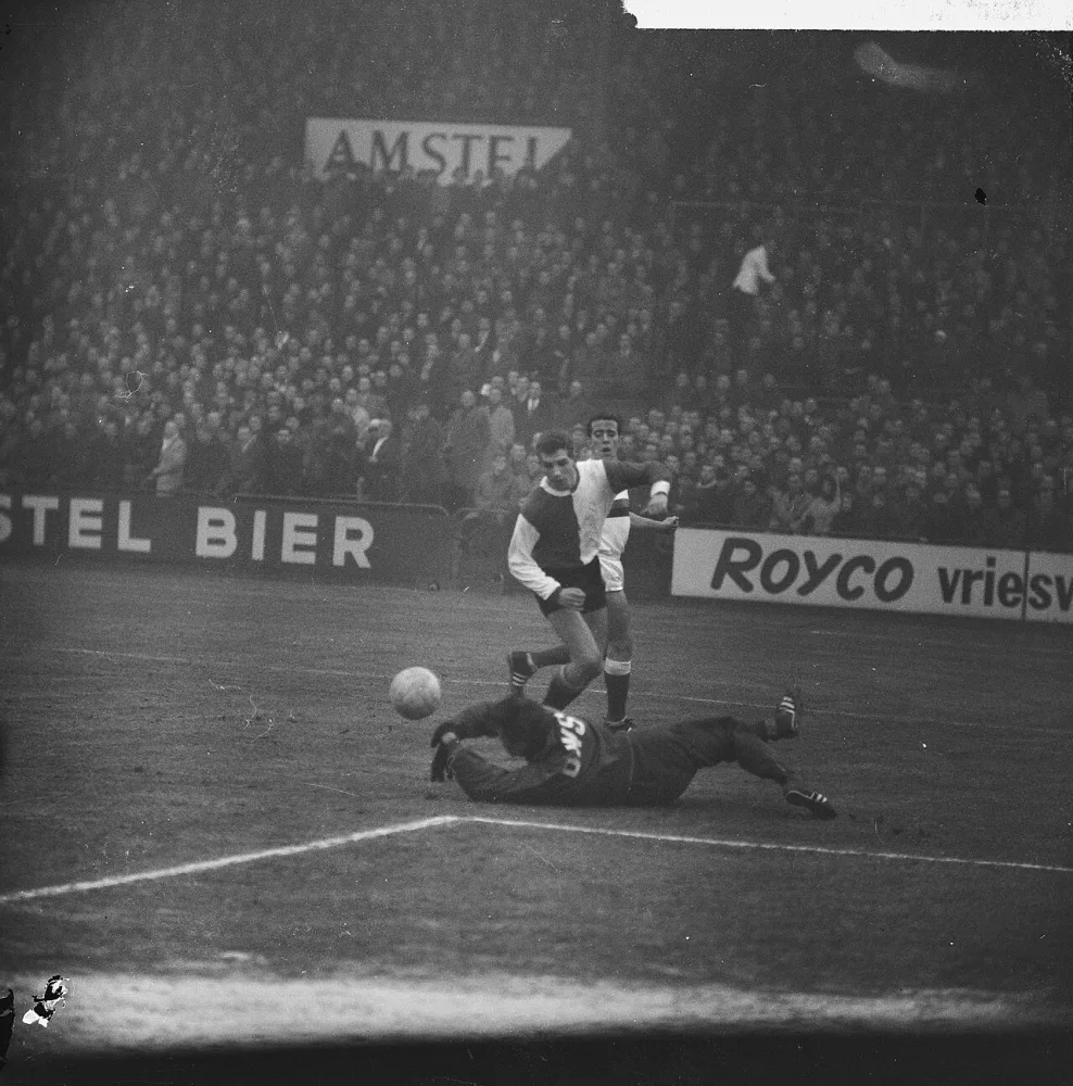 DWS tegen Feyenoord 2-0, Keeper Jongbloed van DWS werpt zich op bal voor de aanstormende Guus Haak, achter hem Burgers (DWS). Foto: Harry Pot / Anefo, Nationaal Archief (CC0).