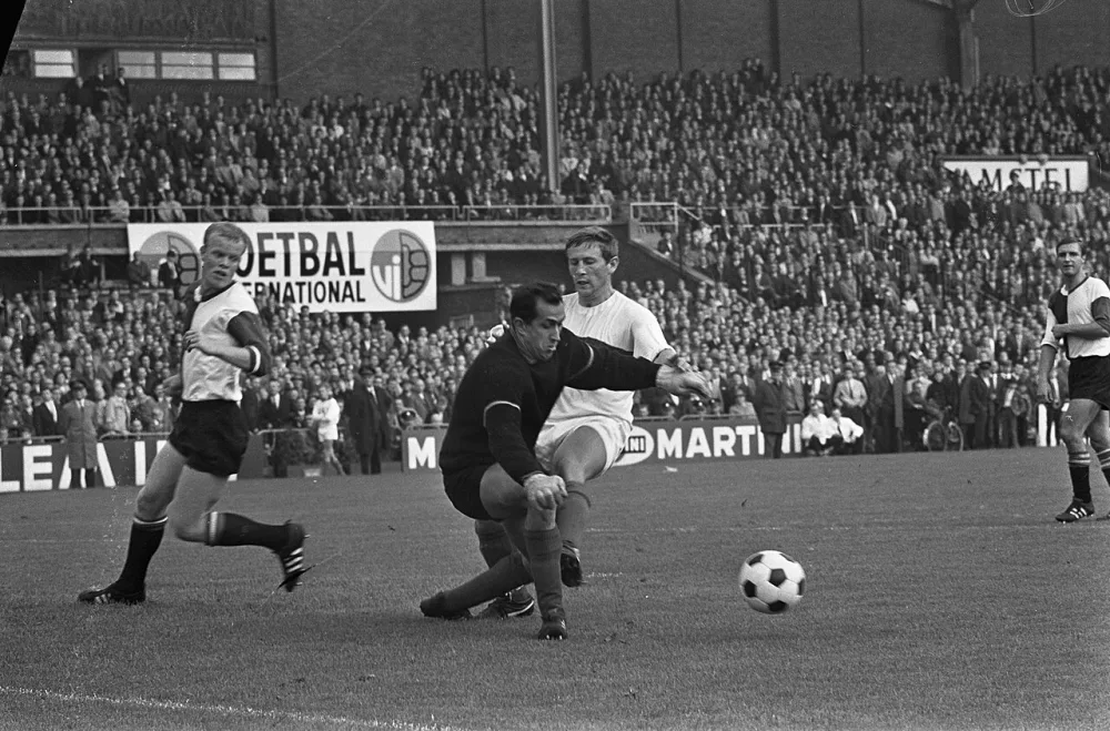 Voetbal. DWS tegen Feijenoord 2-0. Spelmoment, Eddy Pieters Graafland in duel met Frans Geurtsen. Links Piet Romeijn. Rechts in de achtergrond Cor Veldhoen. Foto: Eric Koch / Anefo, Nationaal Archief (CC0).